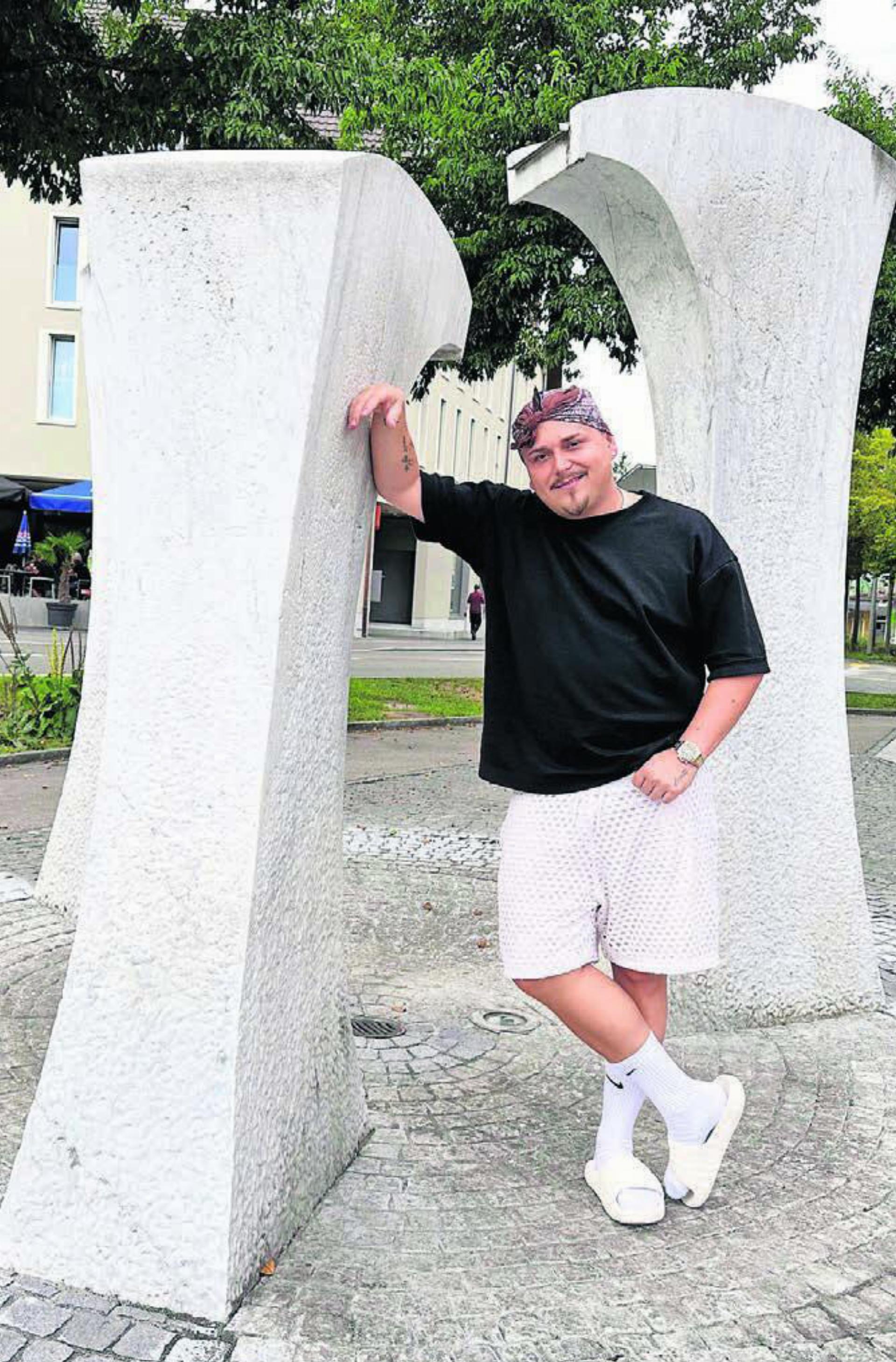 Mit Badelatschen und Bandana auf dem Kopf. Arber Rama beim Dorfbrunnen in Villmergen. Bild: Stefan Sprenger