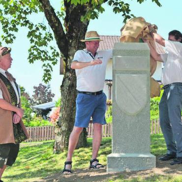 Das Tüpfelchen auf dem i - Der Grenzstein ist in der Heimat angekommen. Nick Wettstein, Ammann Stefan Bossard und Emilio Stecher (v. l.) enthüllen das Kulturdenkmal. Bild: sab