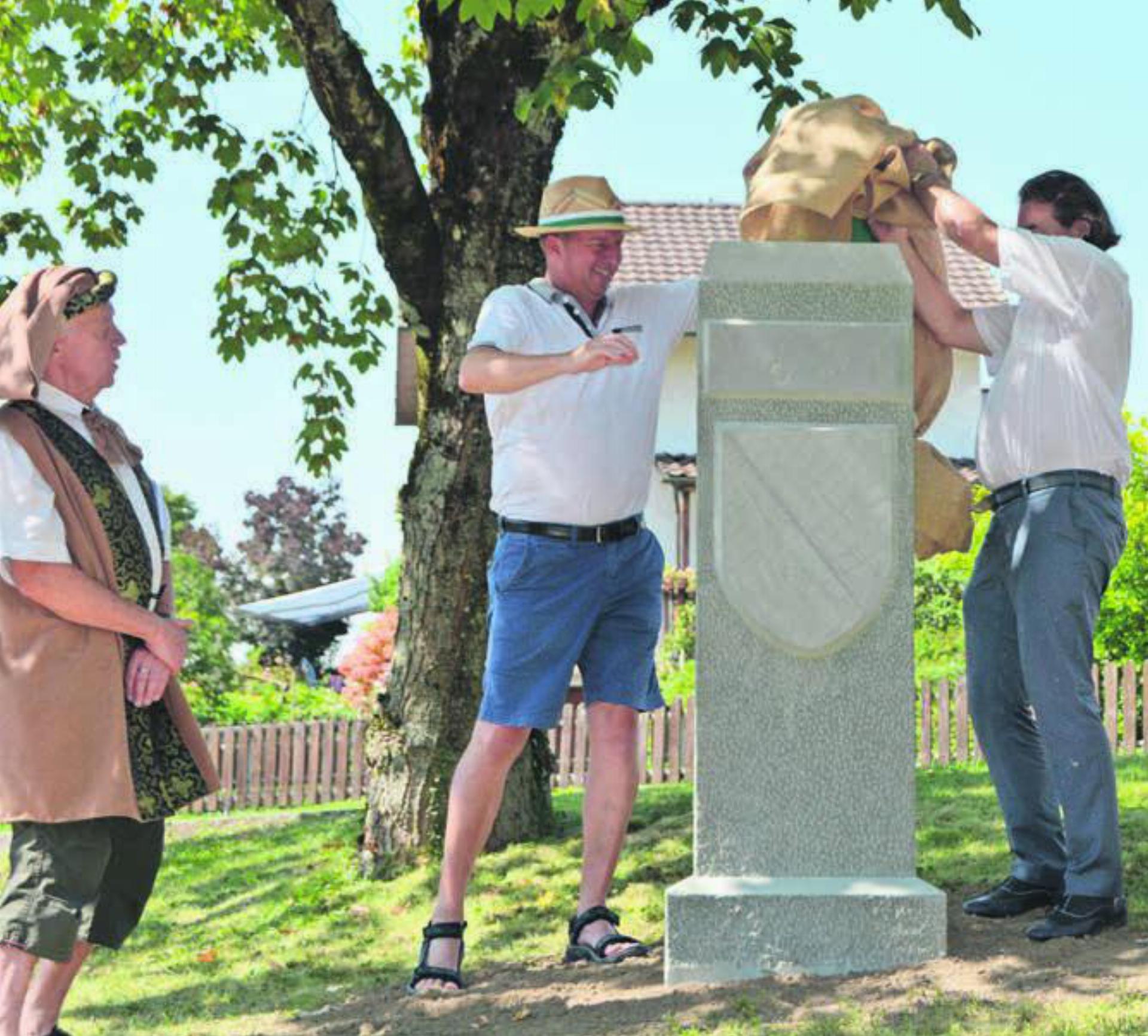 Der Grenzstein ist in der Heimat angekommen. Nick Wettstein, Ammann Stefan Bossard und Emilio Stecher (v. l.) enthüllen das Kulturdenkmal. Bild: sab