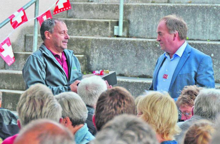 Vizeammann Peter Brütsch überreicht dem Gastredner Alois Huber (links) ein Geschenk – die Bevölkerung spendet Applaus. Bild: Annemarie Keusch